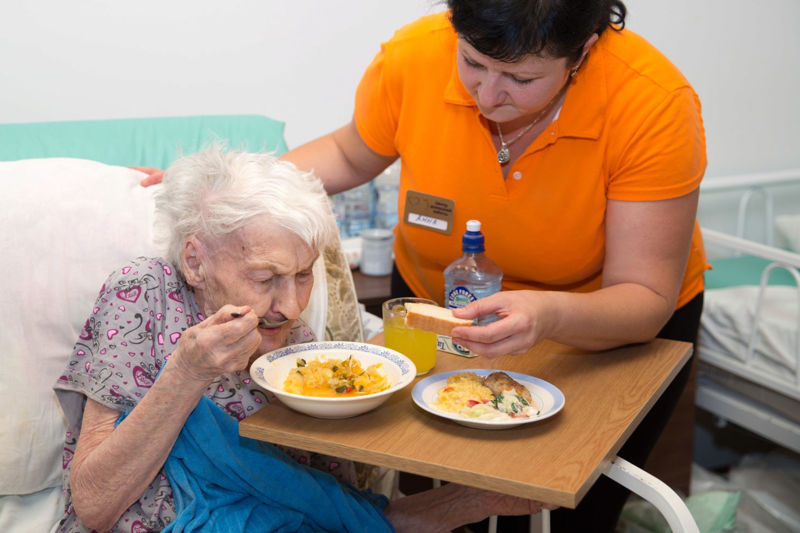 Персонал помогает пенсионерке принимать пищу