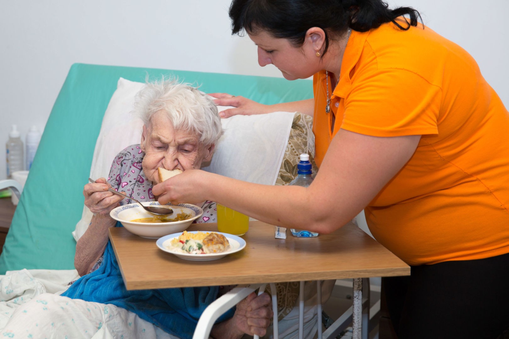 Сиделка кормит супом старую больную женщину